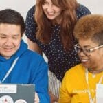 Google AI training: diverse group working on laptops, smiling and collaborating.