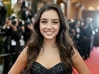 Tilly-Rae Norwood, actrice souriante sur tapis rouge. Cheveux longs bruns, robe noire.