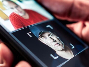 Recognize an AI video: man holding a phone with facial analysis. Guide to detecting fakes.