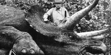 Homme au chapeau posant fièrement à côté d'un Tricératops mort dans la jungle, une image générée évoquant le vrai du faux visuel.