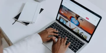 Mains tapant sur un ordinateur portable argenté, écran affichant un navigateur web. Scène de productivité, évoquant les extensions IA pour optimiser le travail.