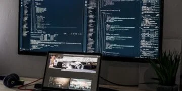 Écran d'ordinateur affichant du code de développement web et un laptop avec un site. Représente l'IA et la programmation.