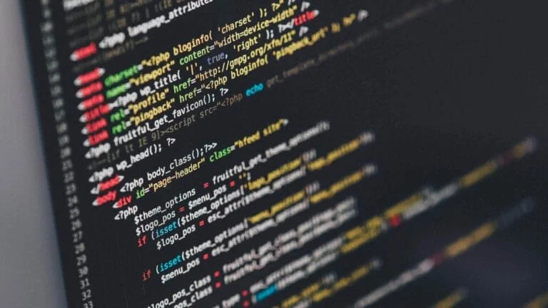 Code source PHP/HTML affiché sur un écran sombre, avec syntaxe colorée. Représente le développement logiciel et l'IA dans le logiciel libre.